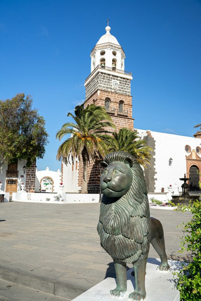 statue de lion et son église avec son clocher dans le village de Teguise à Lanzarote