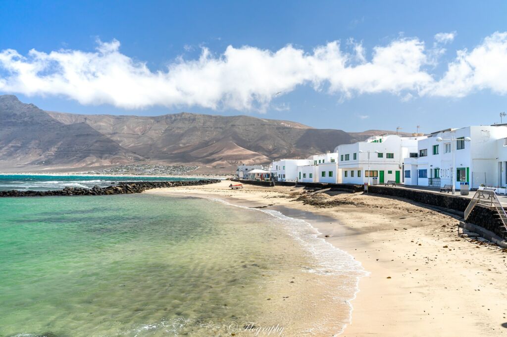 plage de Famara avec des maisons blanches et montagne de volcans de Lanzarote aux canaries