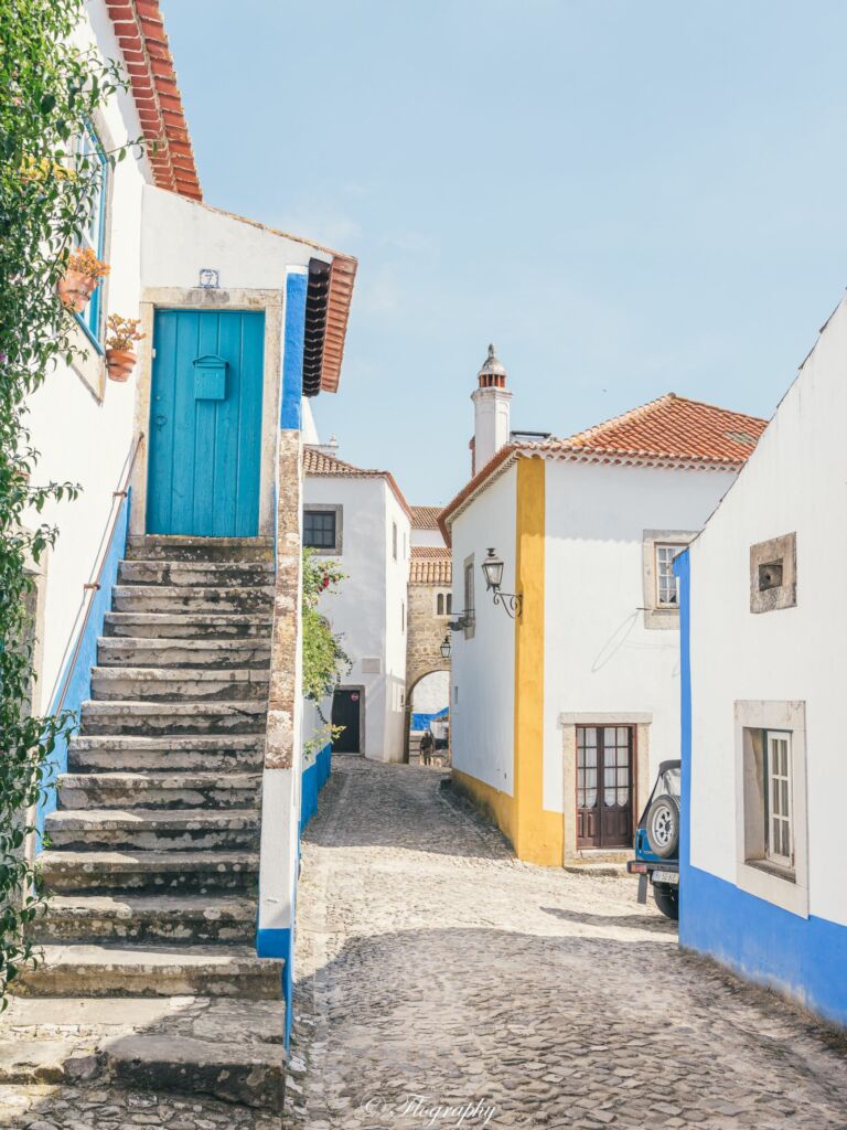 village d'Obidos au Portugal avec des maisons colorées et escalier bleu jaune rue pavés